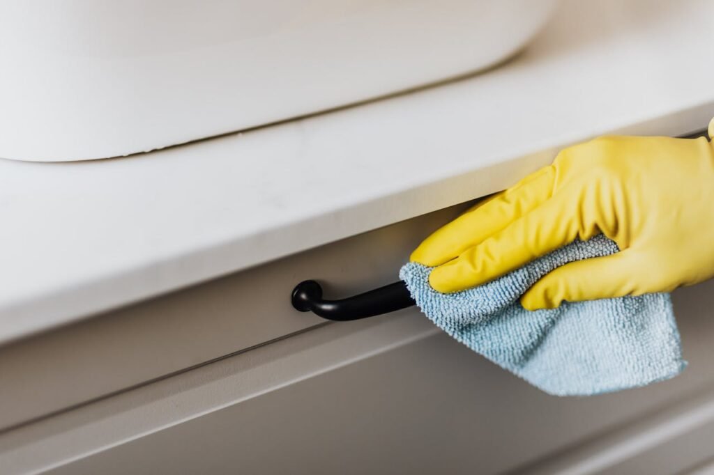 pexels-photo-4239032 person in yellow gloves cleaning handle of cabinet